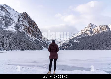 Lago Louise, Alberta, Canada - donna turistica che si trova accanto alla splendida area turistica in inverno nel Parco Nazionale di Banff. Foto Stock