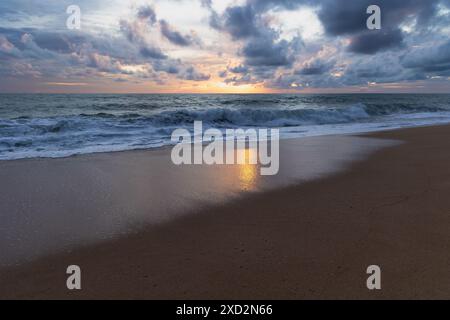 Tramonto incredibile dalla spiaggia della Thailandia. Tramonto con spiaggia sabbiosa con onde. Spettacolare tramonto sul cielo su una spiaggia di sabbia in Thailandia. Nuvole tempestose sulla spiaggia Foto Stock