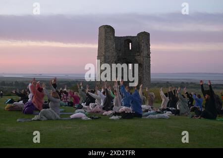 Hadleigh Essex, Regno Unito. 20 giugno 2024. Una lezione di Yoga nei terreni del Castello di Hadleigh nell'Essex nel Regno Unito saluta l'alba la mattina del solstizio d'estate. Il sole sorge alle 04:40 e tramonta alle 21:19 in quello che è il giorno più lungo dell'anno. Il periodo ufficiale del solstizio d'estate nel Regno Unito è alle 21:50 del 20 giugno 2024. Crediti: MARTIN DALTON/Alamy Live News Foto Stock