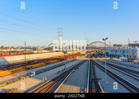 Los Angeles, California - 12 aprile 2024: Vista accattivante del 6th Street Bridge, con binari ferroviari che convergono sotto i suoi archi durante l'oro Foto Stock