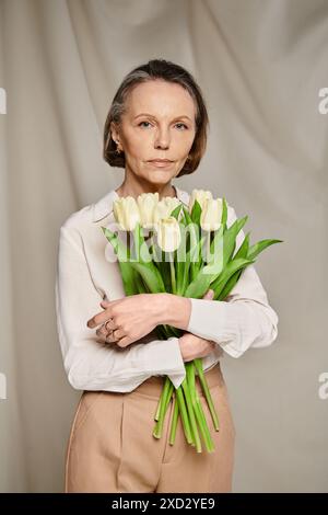 Una donna regala graziosamente un vivace bouquet di tulipani. Foto Stock