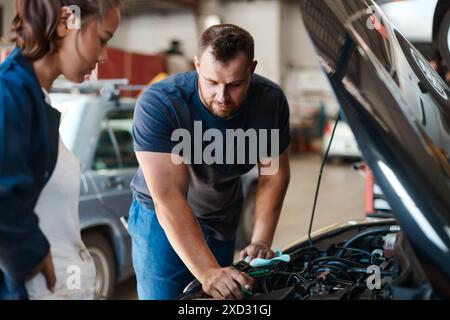 Persone, meccanici e motori di auto con lavoro di squadra, manutenzione o ispezione per problemi relativi al veicolo. Dipendenti, imprenditori o colleghi che operano nel settore industriale, automobilistico Foto Stock