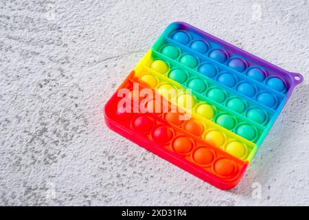 Vista dall'alto del giocattolo sensoriale anti-stress arcobaleno, premi e fallo passare su uno sfondo in pietra Foto Stock