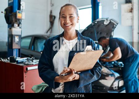Donna, ritratto e appunti in auto per la manutenzione meccanica, i servizi e i controlli di sicurezza in officina. Ingegnere o lavoratore asiatico con lista di controllo Foto Stock