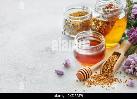 Polline di api e miele biologici crudi in vasetti e fiori di acacia. Foto Stock