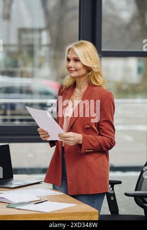 Una donna si trova ad una scrivania, tenendo un giornale. Foto Stock