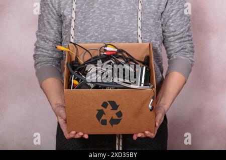 Mani femminili che trasportano scatole di cartone riempite di vecchi dispositivi digitali Foto Stock