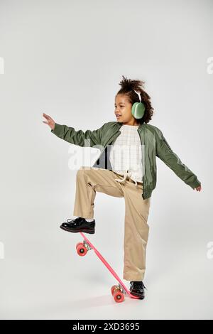 Una giovane ragazza con le cuffie cavalca uno skateboard. Foto Stock