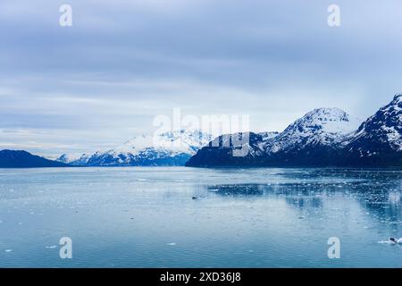 Montagne innevate con riflessi nelle acque ghiacciate. Piccoli iceberg che galleggiano nell'oceano. Alaska. Foto Stock