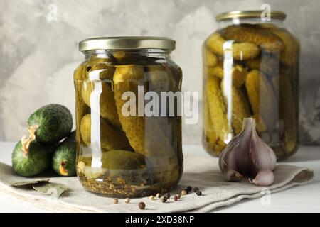 Sottaceti in vasetti, cetrioli freschi e spezie su tavola bianca Foto Stock
