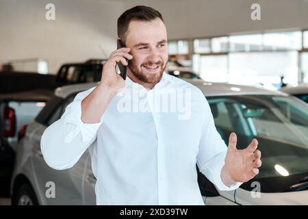 Telefonata, conversazione o persona felice presso la concessionaria per il veicolo, la comunicazione finanziaria o la rete. Consigli, sorrisi o venditori nello showroom che parlano per Foto Stock