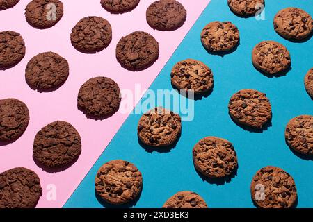 Vista dall'alto dei vari biscotti al cioccolato e dei biscotti al cioccolato doppi posizionati simmetricamente su una superficie rosa e blu a contrasto. L'immagine evidenzia Foto Stock