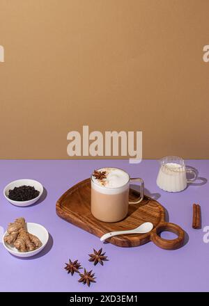 Dall'alto, delizioso chai latte con schiuma cremosa, anice stellato posizionato su uno sfondo vivace con ingredienti freschi Foto Stock