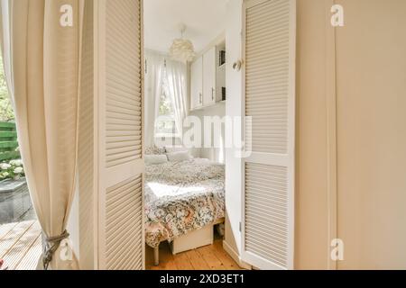 Questa incantevole camera da letto dispone di ampie finestre per la luce naturale, biancheria da letto floreale per un'atmosfera accogliente e ampio spazio portaoggetti con armadi incorporati. Il ne Foto Stock