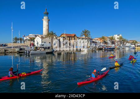 Passaggio di kayak di fronte al faro all'ingresso del porto di Grau-du-ROI | Passage de kayaks de mer devant le phare à l'entrée du port du Grau-du-ROI. Occitanie, Francia Foto Stock