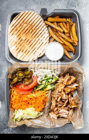 Doner kebab Shawarma su un piatto con patatine fritte e insalata in scatola per andare, da asporto. Sfondo bianco. Vista dall'alto. Foto Stock