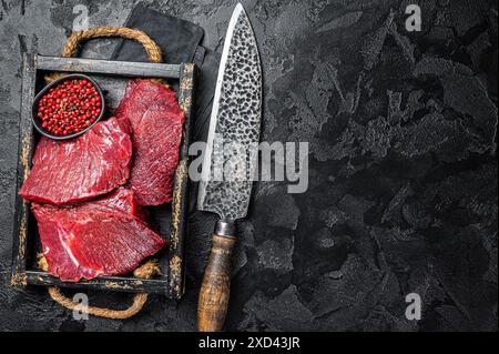 Crudo veleno crudo crudo caro carne, carne di selvaggina. Sfondo nero. Vista dall'alto. Copia spazio. Foto Stock