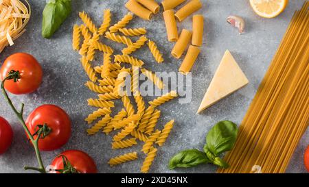 Pasta cruda con ingredienti da cucina su tavola in pietra grigia Foto Stock