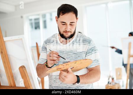 Arte, pittura e uomo a cavalletto in classe, tavolozza e apprendista per progetto creativo. Uomo, pittore e artista per studio di artigianato su tela Foto Stock