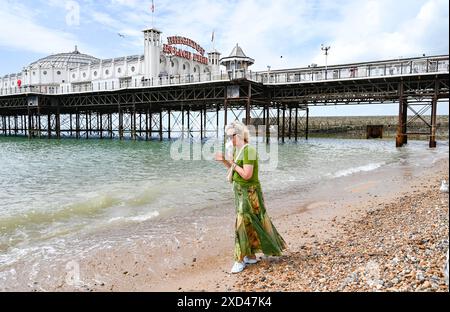 Brighton Regno Unito 20 giugno 2024 - Una donna cerca di gustare un gelato mentre pagaia sulla spiaggia di Brighton sotto il sole prima di essere sbattuta dai gabbiani, dato che il tempo caldo è previsto per la Gran Bretagna per la prossima settimana. : Credit Simon Dack / Alamy Live News Foto Stock