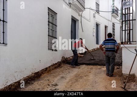 I lavoratori edili rinnovano la superficie asfaltata in una piccola strada, Vejer, Andalusia, Spagna Foto Stock