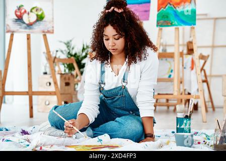 Arte, pittura e donna in studio a pavimento, acrilico e apprendista per progetto creativo. Donna, pittrice e artista per l'artigianato all'accademia Foto Stock