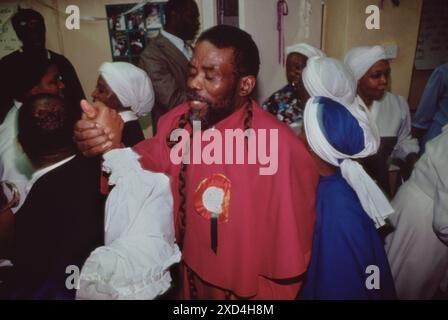 Chiesa Battista spirituale del Monte Sion. Padre Noel alla fine di una chiesa domenicale cammina tra la sua congregazione e dice una breve preghiera con i membri della sua chiesa. Kensal Green, Londra, Inghilterra 1990. 1990 UK HOMER SYKES Foto Stock