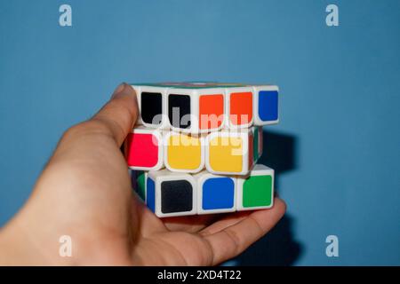 Foto di una persona che regge un rubik su sfondo azzurro Foto Stock