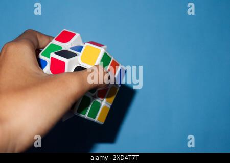 Foto di una persona che regge un rubik su sfondo azzurro Foto Stock