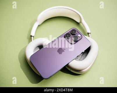 Parigi, Francia - 29 settembre 2022: Un iPhone 15 Pro viola appoggiato su un paio di auricolari bianchi Pro su una superficie verde chiaro, che mettono in risalto il design elegante e l'estetica premium degli ultimi smartphone e accessori audio Apple Foto Stock