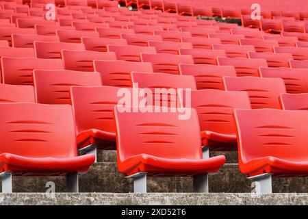 File di posti vuoti in uno stadio. Sedili a teatro in plastica rossa. Foto Stock
