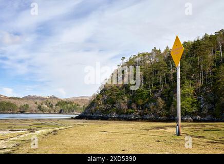 Sulla riva di Loch Moidart, un alto palo segnaletico segnala la vulnerabilità di un cavo telefonico sulla spiaggia. Dorlin Road, Scozia Foto Stock