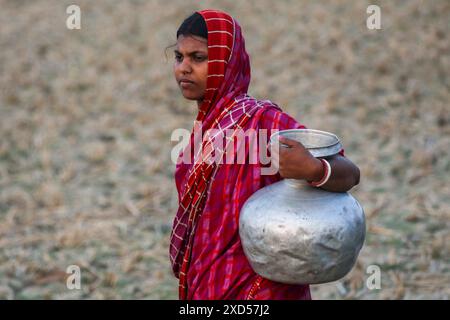 20 giugno 2024, Dacca, Dacca, BANGLADESH: Una donna del Bangladesh che trasporta acqua potabile dopo averla raccolta da una fonte di acqua dolce, camminando molto per raccogliere acqua potabile nella zona costiera di Khulna, Bangladesh. Secondo una ricerca dell'American Geophysical Union, l'innalzamento del livello del mare, che sta influenzando la disponibilità di acqua potabile pulita, causerà la migrazione di circa 1,3 milioni di persone in tutto il paese entro il 2050. Una combinazione di inondazione delle maree, inondazione delle tempeste e intrusione di acqua salata sta portando a un aumento della salinità nelle acque sotterranee e nello stagno di acqua dolce Foto Stock