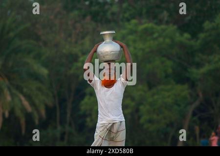 20 giugno 2024, Dacca, Dacca, BANGLADESH: Un uomo bengalese che trasporta acqua potabile dopo averla raccolta da una fonte di acqua dolce, camminando molto per raccogliere acqua potabile nella zona costiera di Khulna, Bangladesh. Secondo una ricerca dell'American Geophysical Union, l'innalzamento del livello del mare, che sta influenzando la disponibilità di acqua potabile pulita, causerà la migrazione di circa 1,3 milioni di persone in tutto il paese entro il 2050. Una combinazione di inondazioni mareali, inondazioni di tempeste e intrusioni di acqua salata sta portando a un aumento della salinità nelle acque sotterranee e negli stagni di acqua dolce, Foto Stock