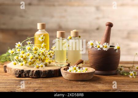 Diversi fiori e bottiglie di oli essenziali su tavola di legno Foto Stock