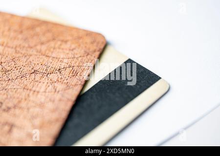 Primo piano di tre carte di credito sventolate su una superficie bianca. Le carte hanno texture e colori diversi, tra cui marrone, nero e beige. Foto Stock