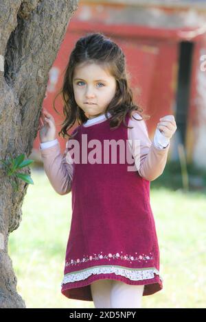 ritratto di una bella bambina seria accanto all'albero nel parco Foto Stock