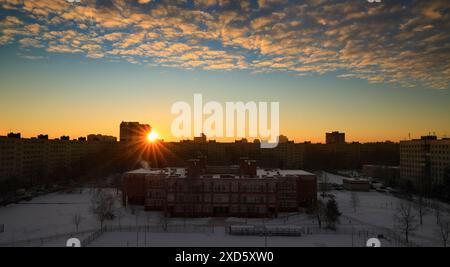 Panorama dell'alba nell'ora d'oro con un'area urbana residenziale e i raggi del sole che sorge Foto Stock