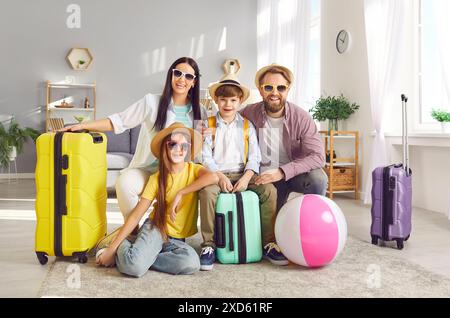 Famiglia felice con bambini seduti sul pavimento con valigie pronte a volare verso un resort tropicale. Foto Stock