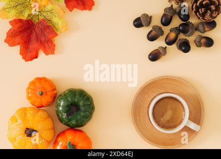 Scena autunnale o autunnale con tazza di caffè, foglie autunnali colorate, varie zucche, pinne e noci con spazio per copiare su sfondo beige pastello. Foto Stock