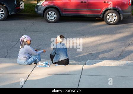 Detroit, Michigan - due donne siedono sul marciapiede fuori dalla galleria d'arte Shepherd durante la sua inaugurazione. Foto Stock