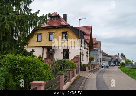 Friesenheim, Germania - 29 aprile 2023: La strada è fiancheggiata da edifici residenziali con tetti piastrellati e automobili. Villaggio tedesco. Foto Stock