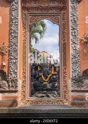 Ganesha con maschere Barong balinesi sedute di fronte al tempio. Decorato per feste religiose con collana di fiori d'arancio e offerta cerimoniale. Foto Stock