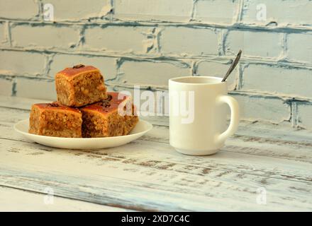 Un piatto con diversi pezzi di deliziosi dolci arabi e una tazza di tè caldo su un tavolo di legno chiaro. Primo piano. Foto Stock