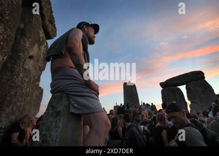 Salisbury, Inghilterra, Regno Unito. 20 giugno 2024. Uno di quelli che celebrano il solstizio d'estate si trova sulla cima di una pietra mentre il sole tramonta a Stonehenge. Stonehenge fu costruita dai primi britannici circa 4000 anni fa per allinearsi al sole sui solstizi. Il solstizio d'estate segna la fine della primavera e l'inizio dell'estate ed è il giorno più lungo e la notte più breve dell'emisfero settentrionale. L'evento è celebrato da migliaia di pagani in tutto il mondo con canti e balli. (Credit Image: © Martin Pope/ZUMA Press Wire) SOLO PER USO EDITORIALE! Non per USO commerciale! Foto Stock