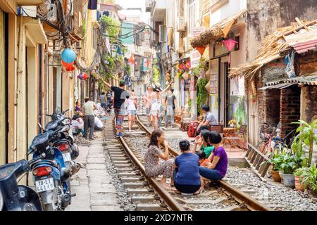 Hanoi, Vietnam - 18 aprile 2019: Donne vietnamite che riposano sulla ferrovia presso Hanoi Train Street. Turisti che scattano foto e aspettano un treno. Foto Stock