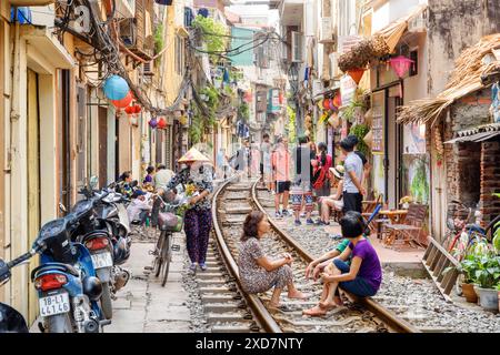 Hanoi, Vietnam - 18 aprile 2019: Donna vietnamita con cappello tradizionale che cammina lungo una stretta strada del quartiere vecchio di Hanoi. Foto Stock