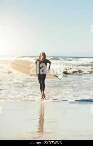 Ritratto, uomo e surfista che cammina in mare durante le vacanze estive, le vacanze e i viaggi in California. Tavola da surf, persona e spiaggia per fitness, allenamento e.. Foto Stock