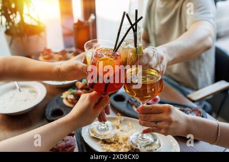 il primo piano del brindisi festivo mostrando le mani che tengono vari drink, cocktail e vino. l'atmosfera di un pasto tra amici o familiari. concetto di camaraderi Foto Stock