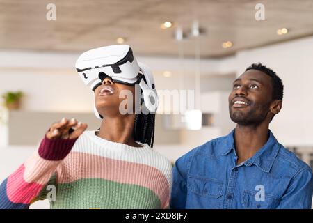 Utilizzando il visore VR, donna che esplora il mondo virtuale mentre l'uomo la guarda con un sorriso Foto Stock
